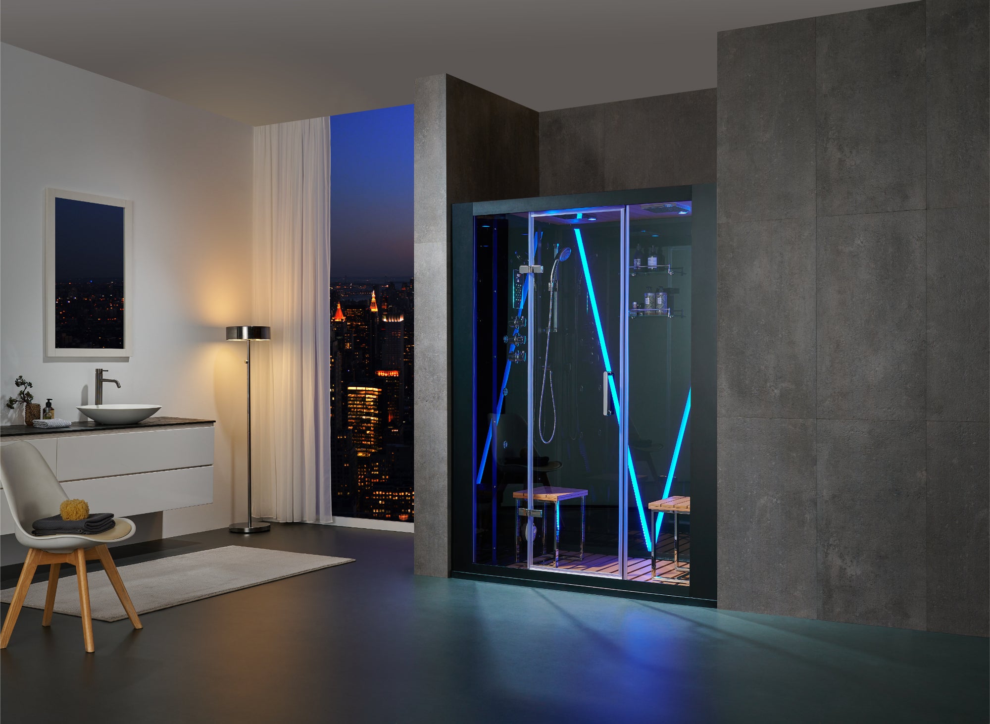 A modern bathroom interior with a large glass walk-in shower enclosure illuminated by vivid blue LED lighting, set against dark textured walls and a city skyline visible through a window at dusk.