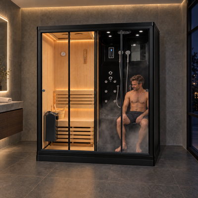 A man sits inside a large black-framed indoor sauna and shower cabin with wood benches, steam, and warm ambient lighting in a modern bathroom setting.