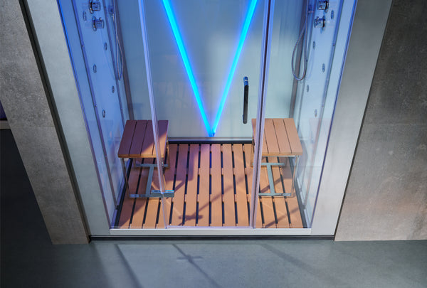 A glass steam room or sauna with a wooden slatted floor, two wooden benches, and bright blue LED lighting inside, shown against a gray concrete wall.