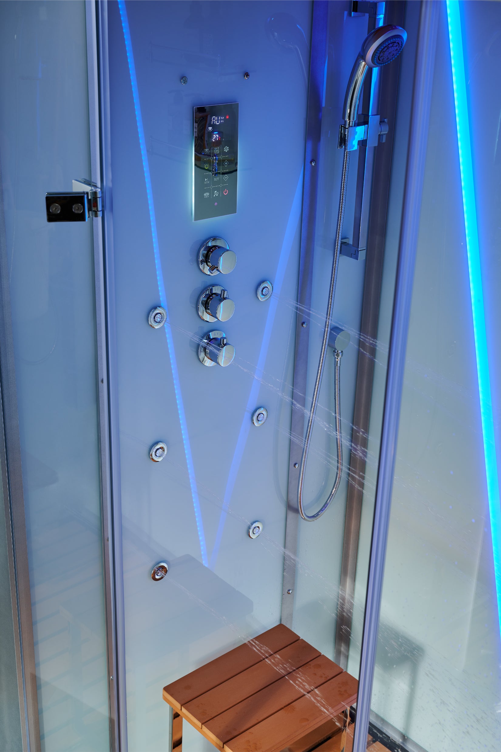 A modern glass shower cabin with a blue-lit control panel, handheld shower, and a small wooden bench inside.