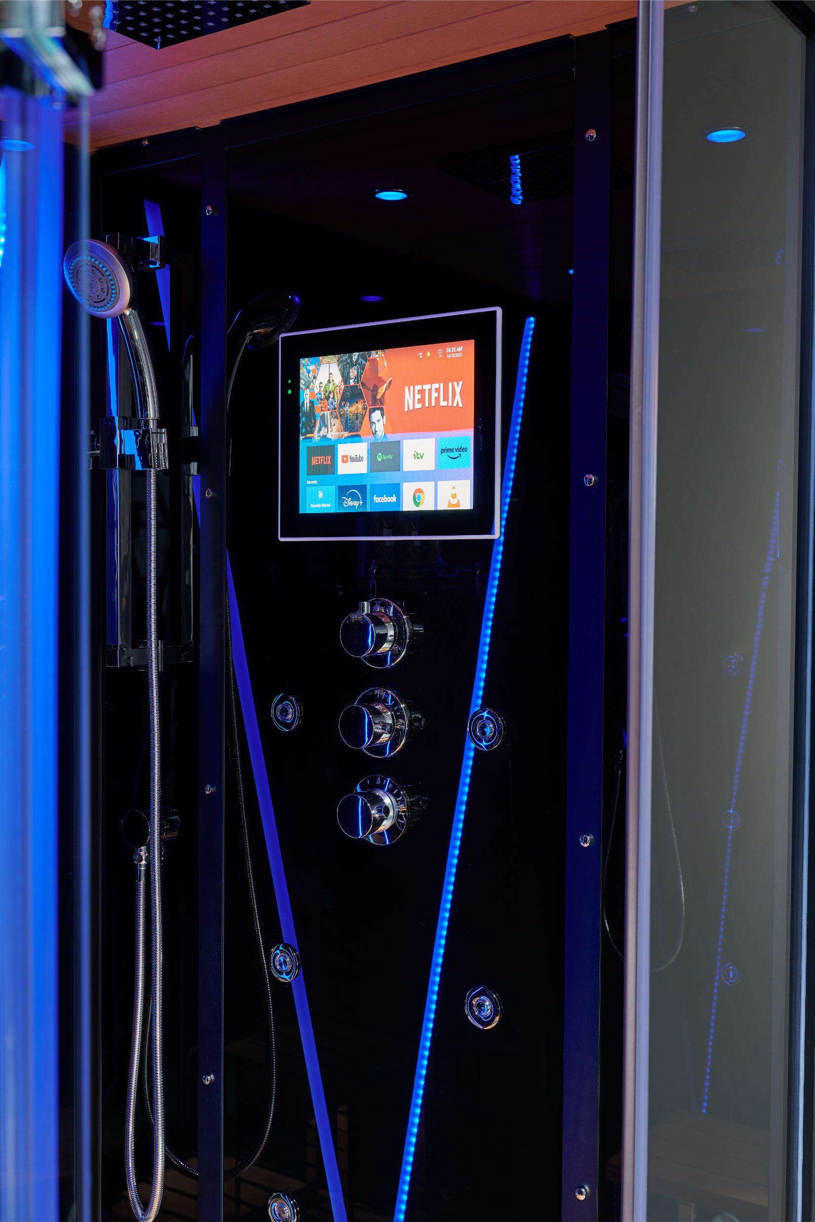 A modern black hot tub or spa cabinet with a digital control screen showing Netflix and other app icons, illuminated by blue LED lights. A handheld shower head is mounted on the left side, and the cabinet interior features a sleek black finish with chrome controls.