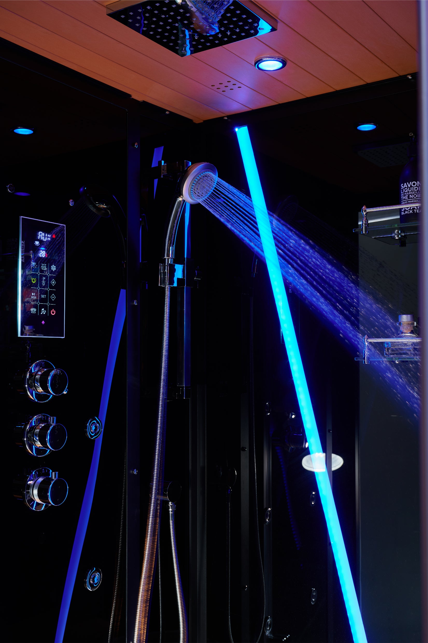 A modern shower system with a handheld showerhead spraying water, illuminated by bright blue LED lighting in a dark bathroom setting.