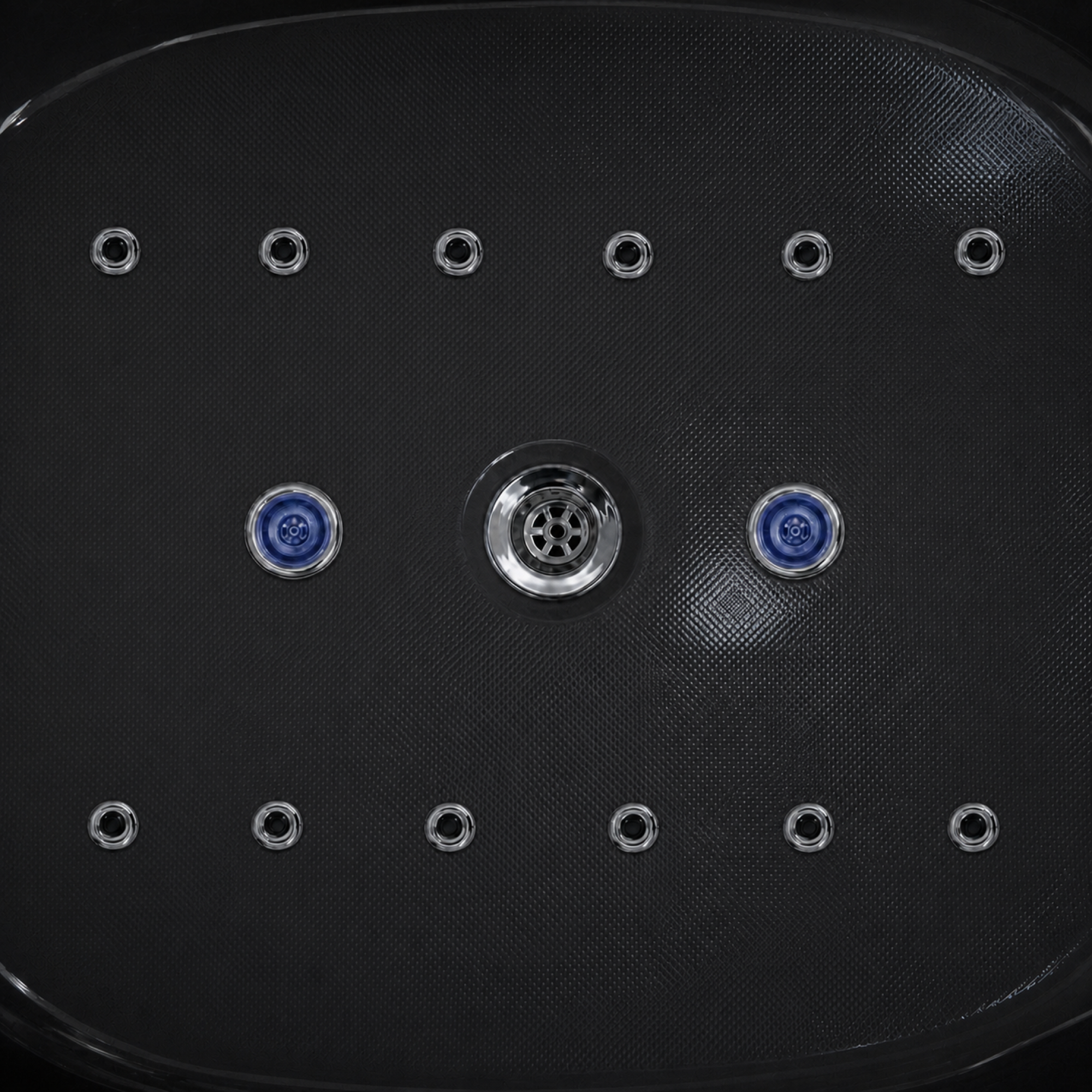 Close-up of a black textured spa or hot tub jet panel with multiple circular jets, including two blue-accented jets and a central chrome jet.